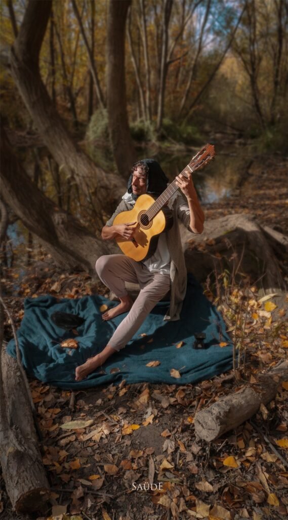 Persona tocando la guitarra sentada sobre una manta en el bosque, TunaTi